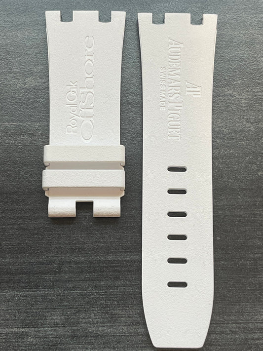 Two white watch straps neatly placed on a wooden table surface.