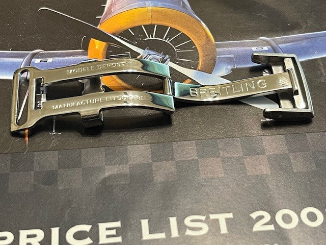 Close-up of polished Breitling watch clasp on price list background