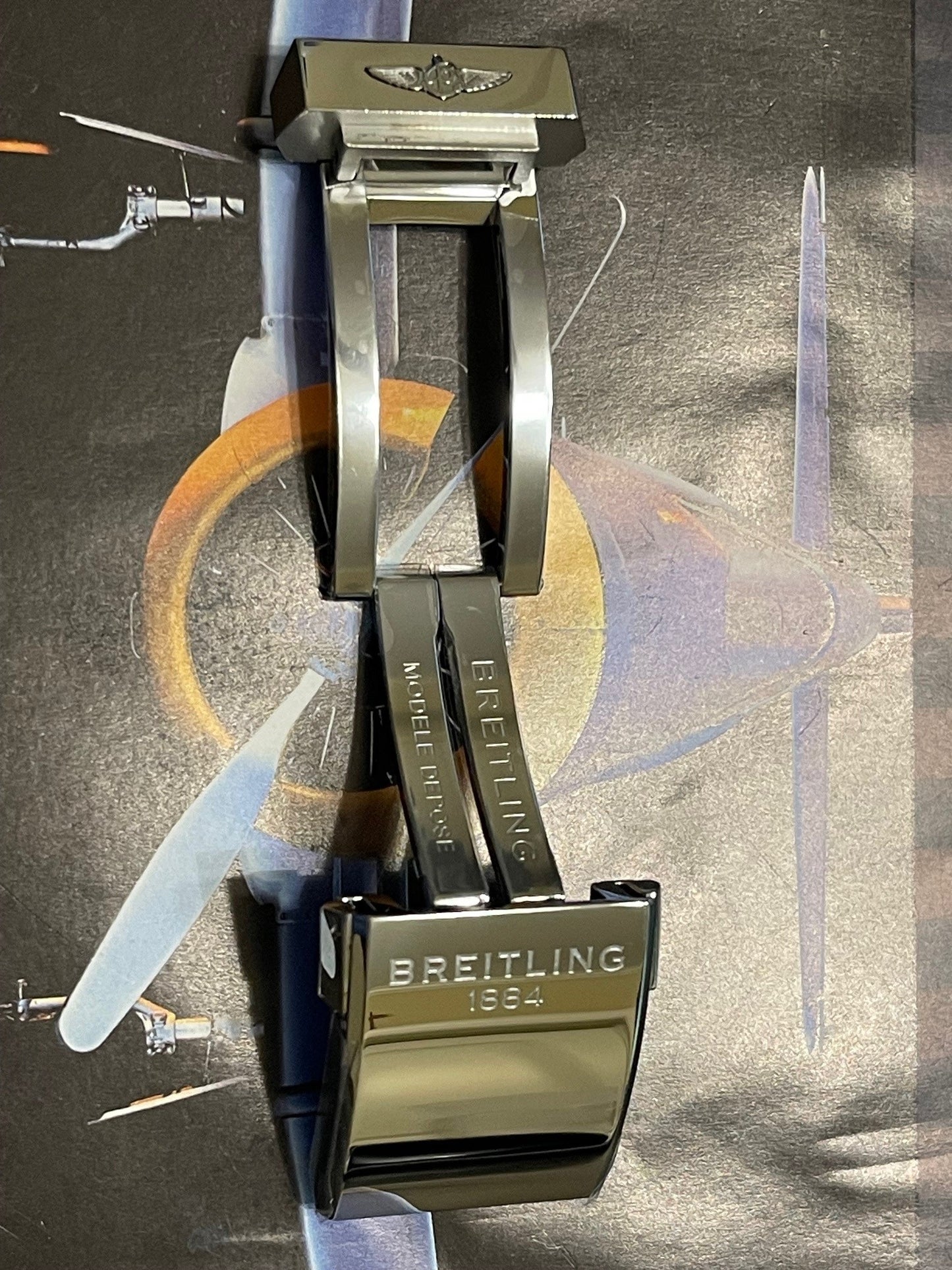 Polished Breitling watch clasp with logo on aviation-themed background