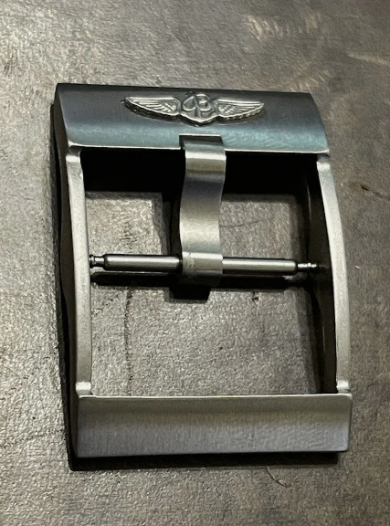 Panerai buckle with winged emblem resting on dark textured surface