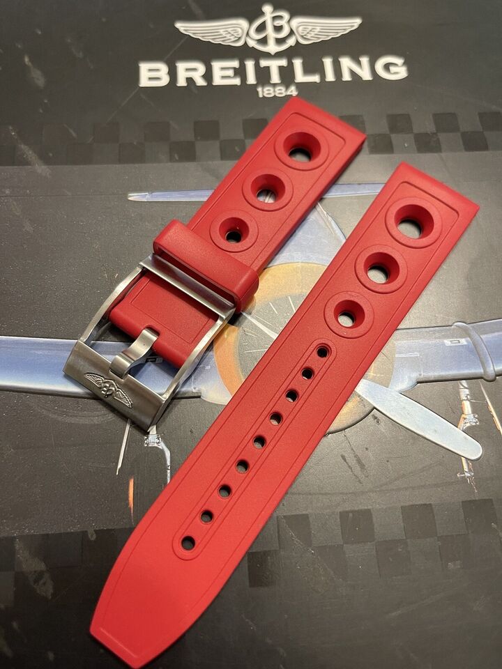 Breitling red rubber watch strap displayed over vintage aircraft logo backdrop
