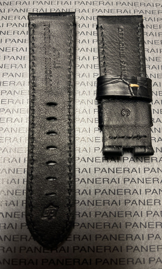 Close-up of black leather watch strap split in two with embossed branding on Panerai logo background