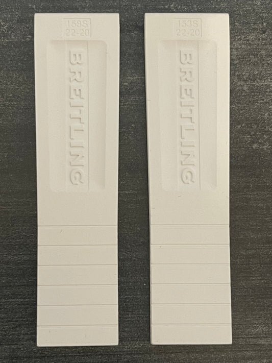 Two white plastic bookmarks resting on a wooden table surface.