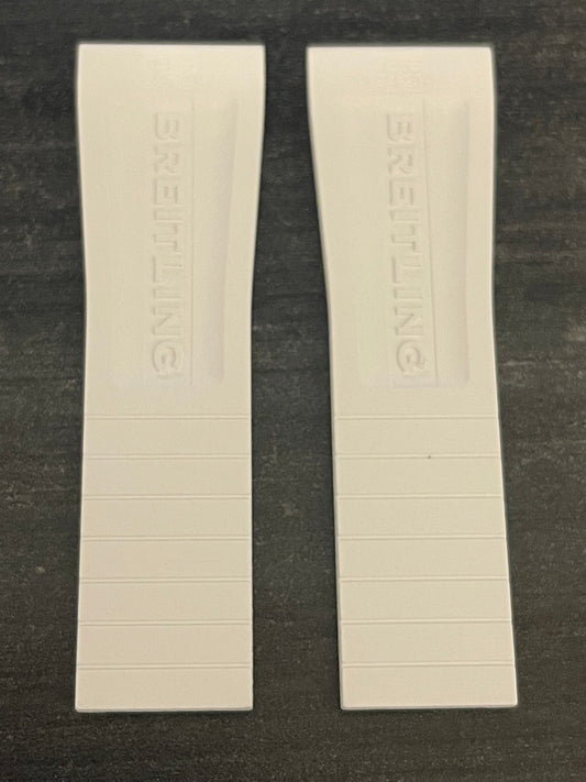 Two white plastic watch straps resting on a table surface.