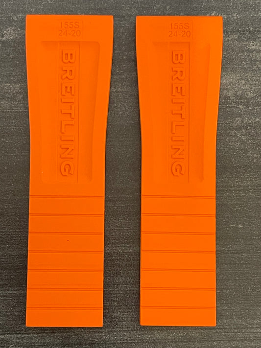 A pair of orange rubber watch straps, both embossed with the brand name "Breitling."