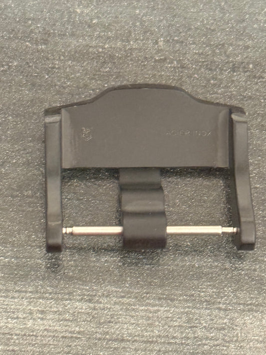 A black plastic buckle resting on a wooden table surface.